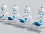 a group of white robots sitting on top of laptops