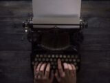 person holding white and black typewriter