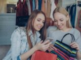 Two women shop and look at a phone.