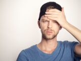 man in blue crew neck shirt covering his face