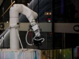 A white robotic arm operating indoors with a modern design and advanced technology.
