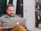 man smiling and using MacBook