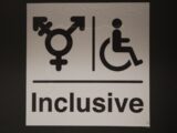 A white sign with a black and white image of a person in a wheelchair
