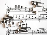 Scattered puzzle pieces with musical notes on sheet music.