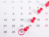 a calendar with red push buttons pinned to it