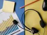 A flat lay image depicting an office desk with a headset, chart, and stationery for business use.