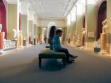 a man and woman sitting on a bench in a museum