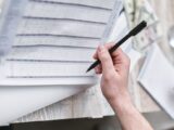 A close-up of a person holding a pen reviewing a financial document with cash visible, ideal for business themes.